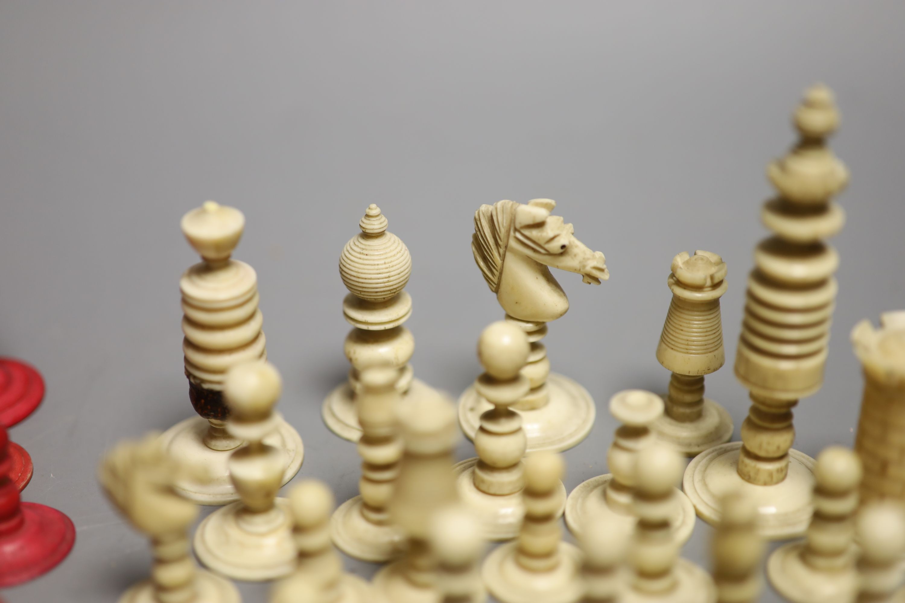 A set of 19th century red stained and natural bone chess pieces and a collection of etched mother of pearl bezique counters